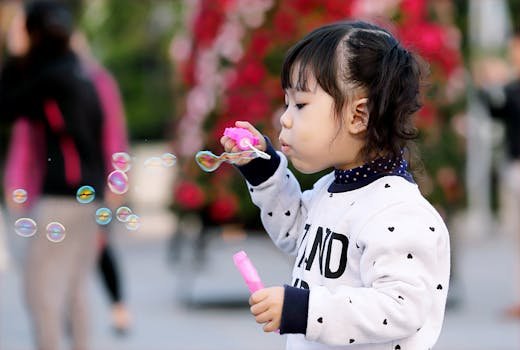 A young girl joyfully blowing bubbles outdoors, capturing a playful moment of innocence and joy.